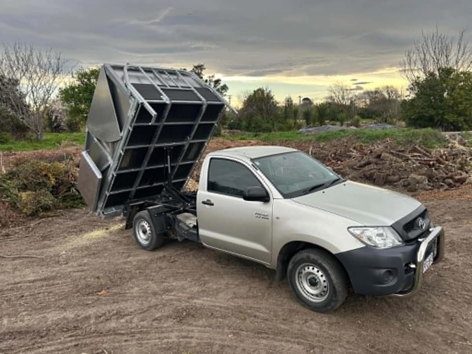 Topline tipper truck with the deck raised, ready to take away green waste